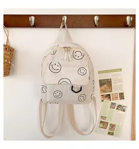 Detail of white corduroy backpack with smiley face pattern hanging on wooden hook