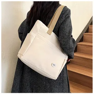 Detail view of canvas tote bag featuring khaki straps and 'good luck' circular patch
