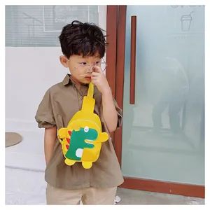 Petit garçon asiatique portant un sac de poitrine dinosaure jaune devant une boutique