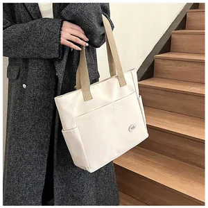 Detail of the side pocket and khaki strap on the large cream canvas tote bag