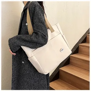 Detail view of canvas tote bag with contrast strap and 'good luck!' circular logo patch