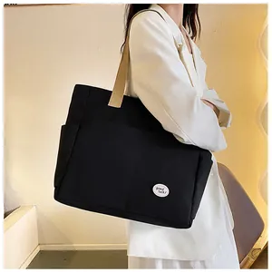 Detail of black canvas tote bag with Good Luck label and khaki shoulder strap