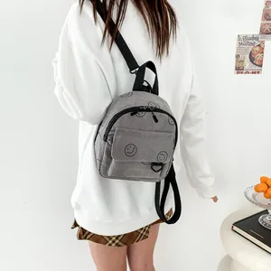 Gray corduroy backpack with smiley face prints and adjustable black shoulder straps