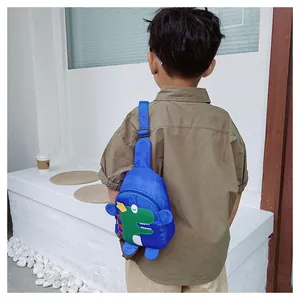 Détail du sac de poitrine bleu pour enfants avec broderie dinosaure porté sur un banc blanc