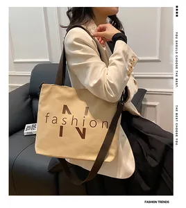 Detailed view of beige canvas tote bag with brown straps and detachable shoulder strap