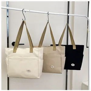 Close-up of thick canvas tote bags in white, khaki, and black with front utility pockets