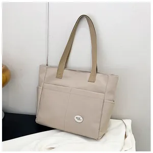 Detail shot of beige canvas tote bag featuring two front pockets and good luck patch
