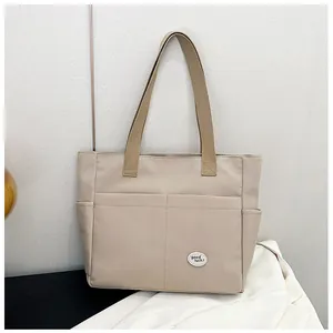 Detail of khaki canvas tote bag with front pockets and 'good luck' circular patch