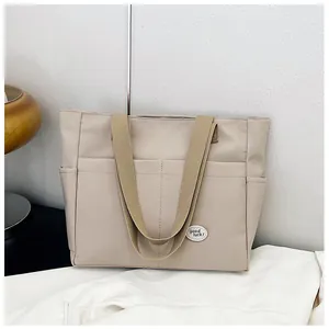 Close-up of thick beige canvas tote bag with front pockets and 'good luck' patch