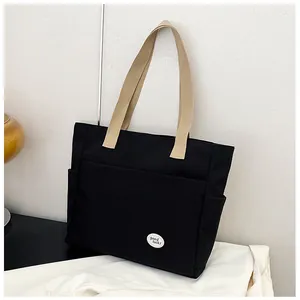 Detail of black canvas tote bag showing side pocket and good luck round logo badge