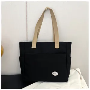 Detail of black canvas tote bag with side pockets and lucky slogan patch detail