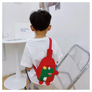Sac bandoulière dinosaure rouge pour enfant porté par un modèle pour voir la taille