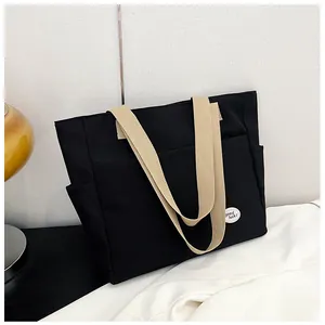 Close-up of black canvas tote bag with side pockets and round good luck badge detail