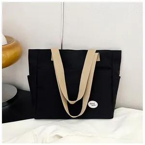 Detail of black canvas tote bag with contrast beige straps and good luck emblem