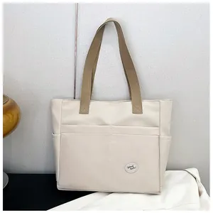 Detail view of a beige canvas tote bag showing storage pockets and good luck patch