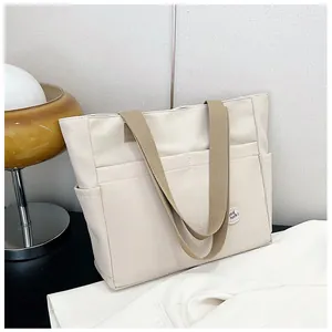 Detail of canvas tote bag with brown straps and 'Good luck!' label on outer pocket