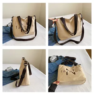 Detail view of khaki canvas tote bag showing wide brown straps and fashion print logo