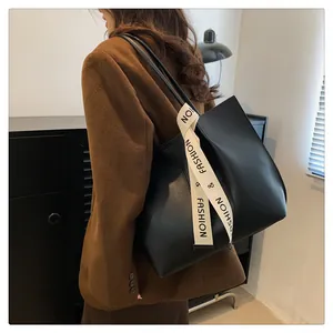 Zwarte leren shopper met canvas lint aan het handvat gedragen door model in blazer