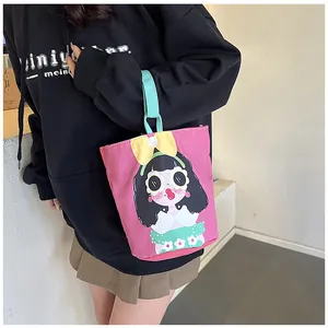 Detail of pink canvas bucket bag with cute cartoon girl illustration and blue handles