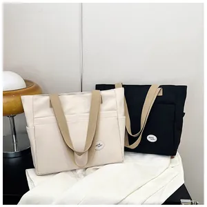 Detail view of canvas tote bags with contrast straps and front pockets in black and white