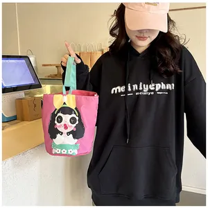 Detail of canvas bucket bag with cartoon girl illustration and yellow 3D bow accent