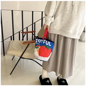 Detail of canvas bucket bag with cute bear and tomato illustration held by a model