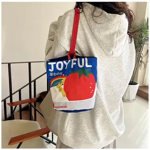 Detail of canvas bucket bag with cute berry illustrations and red straps on shoulder