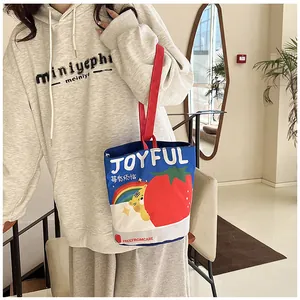 Detail of canvas bucket bag featuring cute strawberry illustration and red handles