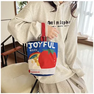 Detail of canvas bucket bag featuring colorful joyful tiger illustrations and red handles