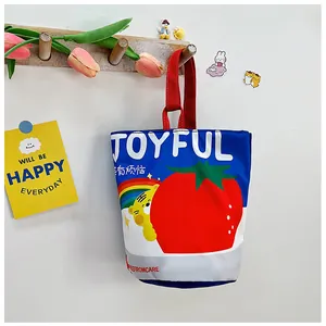 Detail of canvas bucket bag with vibrant tiger and tomato print hanging on a wooden hook
