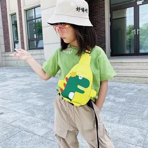 Sac bandoulière dinosaure jaune pour enfant porté par un petit garçon en extérieur