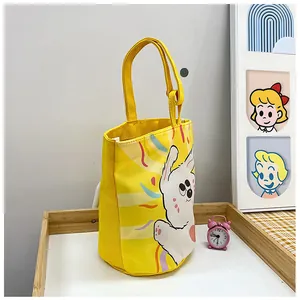 Detail of yellow canvas bucket bag with cute cartoon rabbit illustration and fabric texture