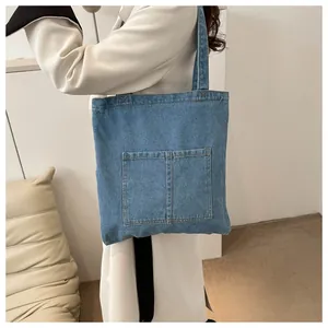 Detail view of denim tote bag with two front pockets and durable fabric texture