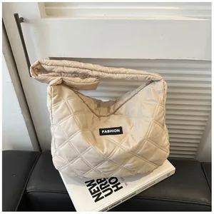 Detail van beige gewatteerde hobo-tas met grote ruiten en een modieus label erop