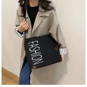 Detailed view of black canvas tote bag with white FASHION print and leather corners
