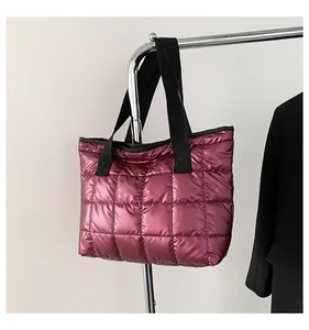 Close-up of metallic pink quilted tote bag with wide black handles on a hanger