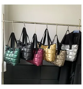 Close-up of quilted down tote bags in various metallic colors hanging on a rack