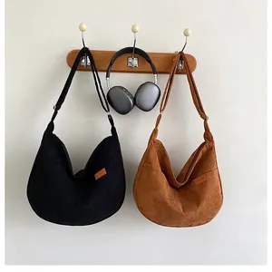 Detail of corduroy hobo bags in black and tan with adjustable straps and SPORT label
