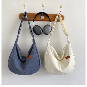 Detail of corduroy crossbody bags in navy and cream showing adjustable wide shoulder straps