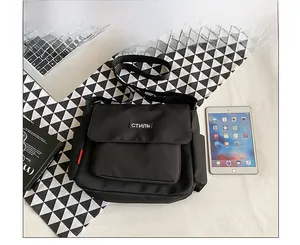 Detailed top view of black nylon messenger bag with tablets and books on patterned background