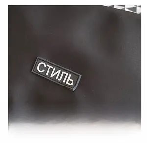 Macro detail of black nylon messenger bag with white STYL Cyrillic character patch