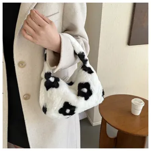 Dettaglio della borsa in peluche bianca con motivo floreale su un tavolo di legno