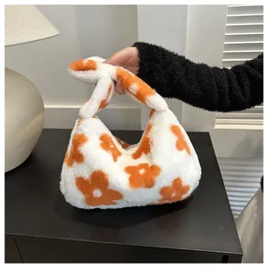 Dettaglio borsa a mano in peluche bianca con motivi a fiori arancioni e manico annodato