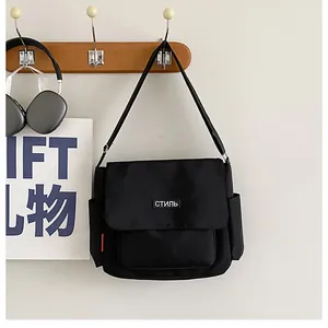 Detail view of black canvas messenger bag with white cyrillic script and side pockets