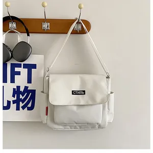 Macro shot of white canvas messenger bag with Stil text and red side label detail