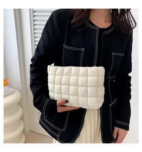 Detailansicht der cremefarbenen gesteppten Kosmetiktasche von einem Model gehalten