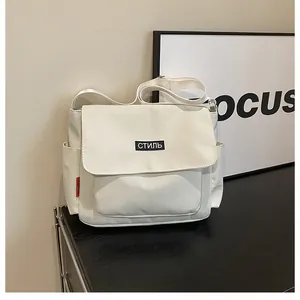 Detail of white canvas messenger bag featuring a black label and red side tag