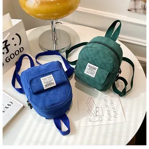 Detail of blue and green corduroy mini backpacks featuring fashion instinct woven labels