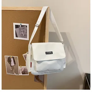 Detail of white canvas messenger bag featuring a Russian style woven label and wide strap
