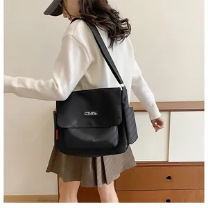 Close-up of black messenger bag with white СТИЛЬ patch and adjustable shoulder strap